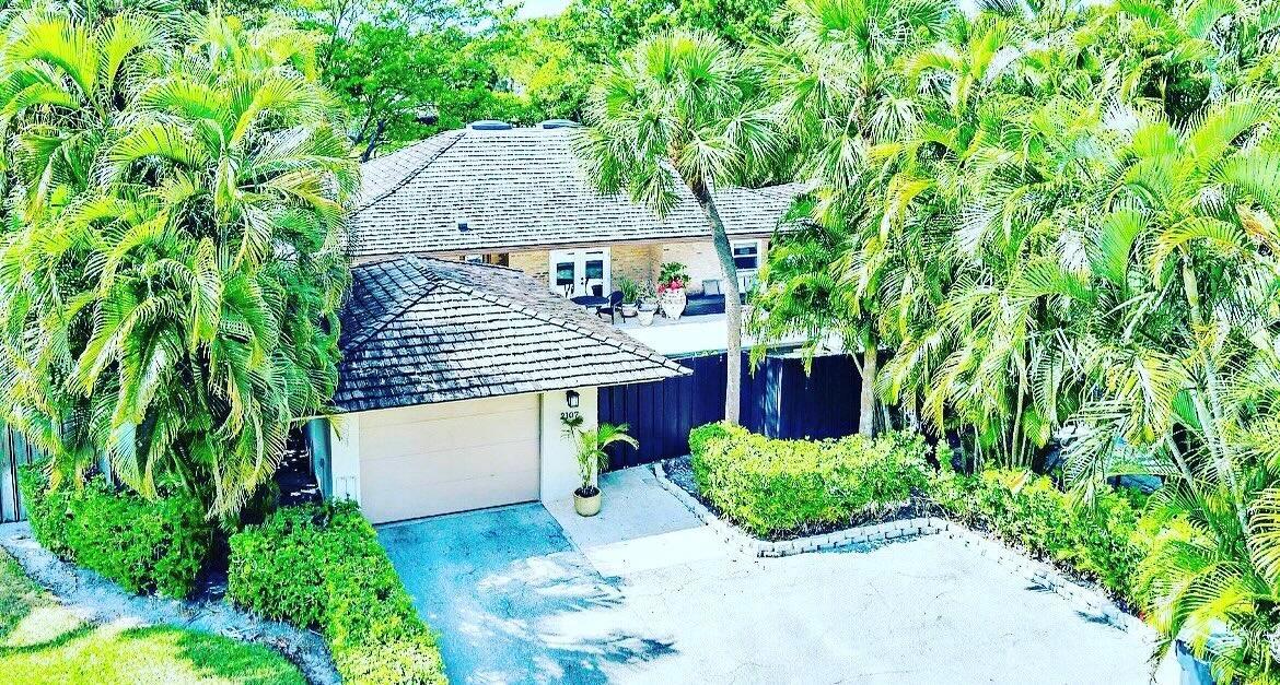 An aerial view of a house with a shingled roof, garage, and lush palm trees — 2107 Wightman Drive, Wellington FL 33414, WELLINGTON, FL