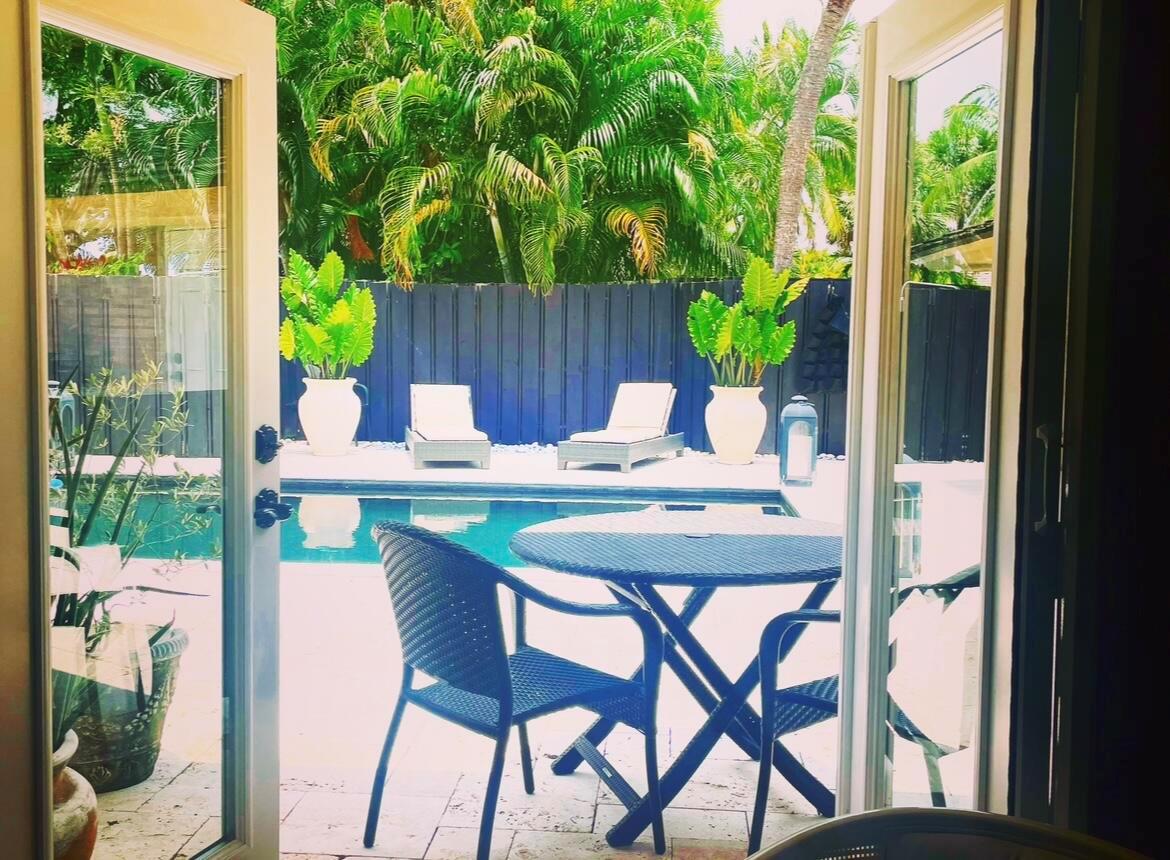 A view from an open doorway looking out onto a patio with a swimming pool — 2107 Wightman Drive, Wellington FL 33414, WELLINGTON, FL