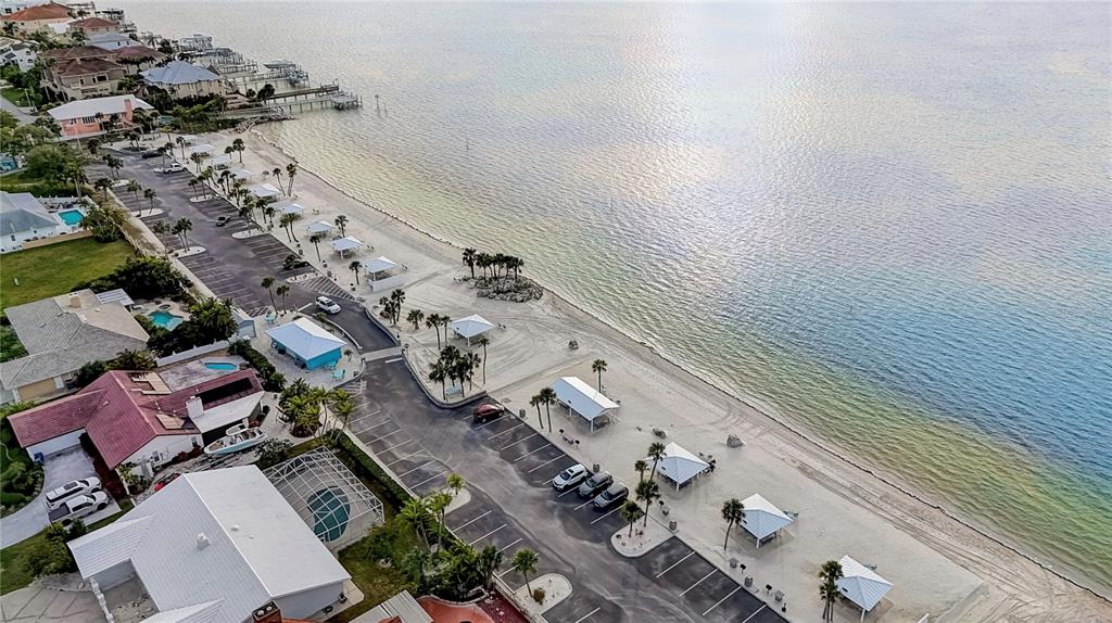 An aerial view shows a coastal parking lot adjacent to a sandy beach and water — 4812 JASPER DRIVE UNIT 105, NEW PORT RICHEY, FL