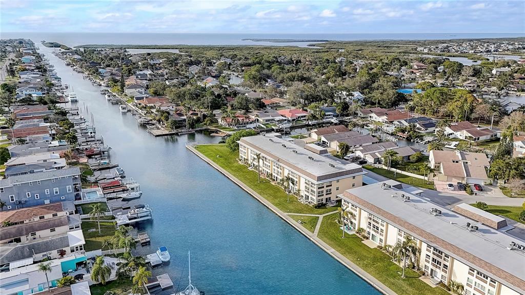 An aerial view shows a canal lined with residential buildings, docks, and boats — 4812 JASPER DRIVE UNIT 105, NEW PORT RICHEY, FL