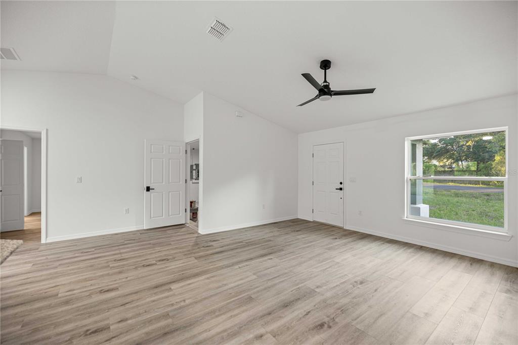 An empty room with white walls, vaulted ceilings, a ceiling fan, and wood-look flooring — 11380 SE 123RD AVENUE, DUNNELLON, FL