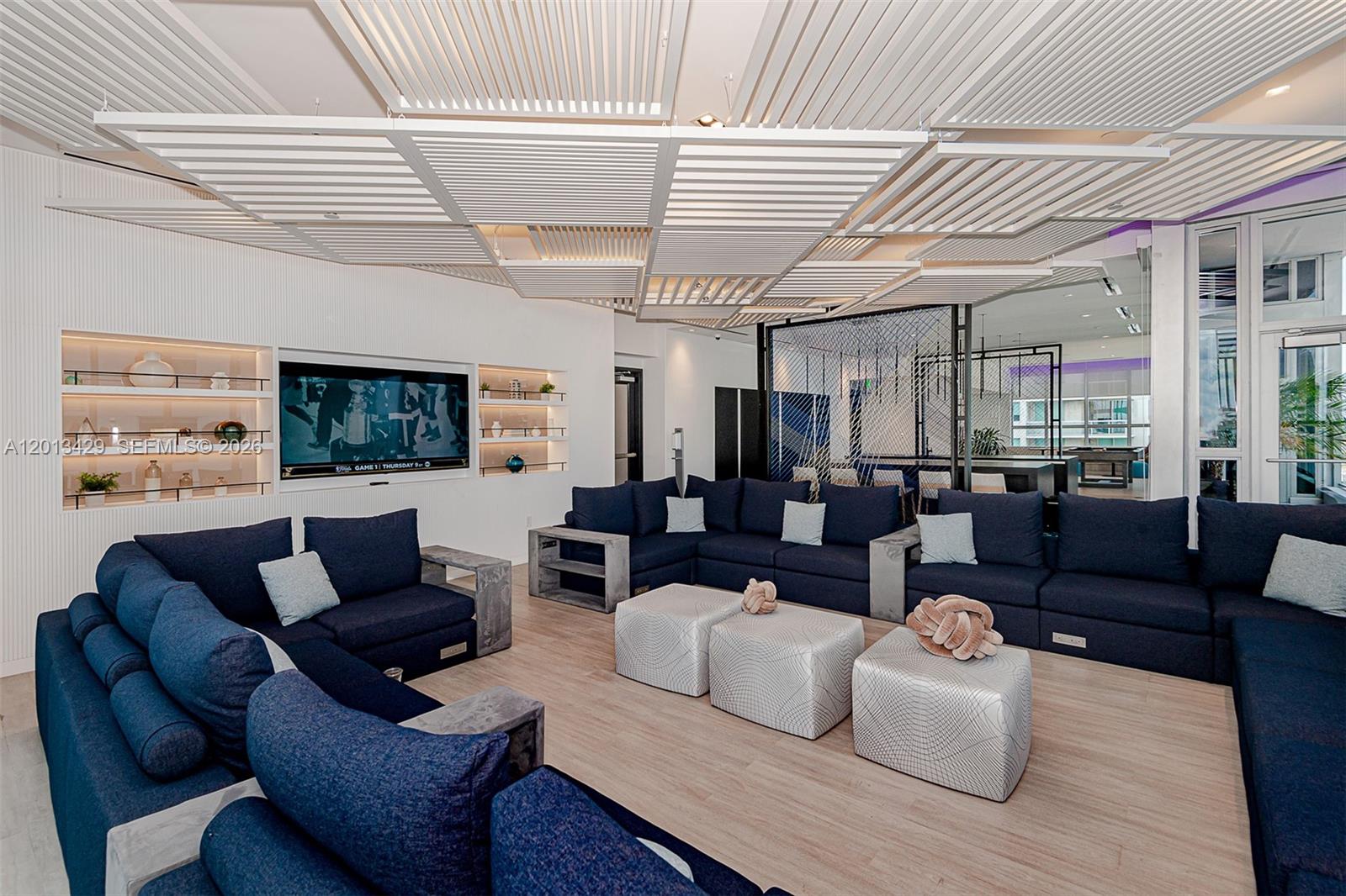 A lounge area features dark blue sectional sofas, light wood flooring, and a slatted ceiling — 227 NE 2nd St # 2206, Miami FL 33132, MIAMI, FL
