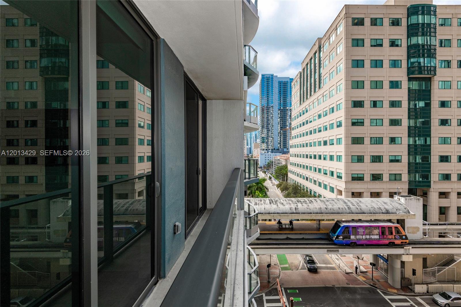 A balcony view overlooks a city street with a passing monorail train and nearby buildings — 227 NE 2nd St # 2206, Miami FL 33132, MIAMI, FL
