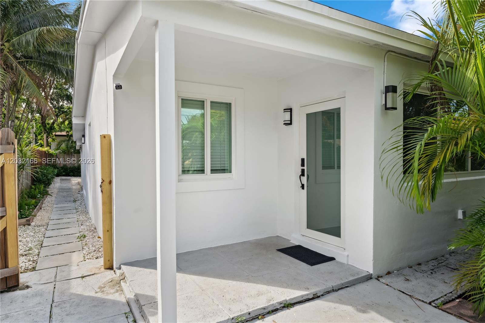 A white exterior building features a covered concrete porch, a glass door, and a window — 1480 NE 117th St # 1480, Miami FL 33161, MIAMI, FL