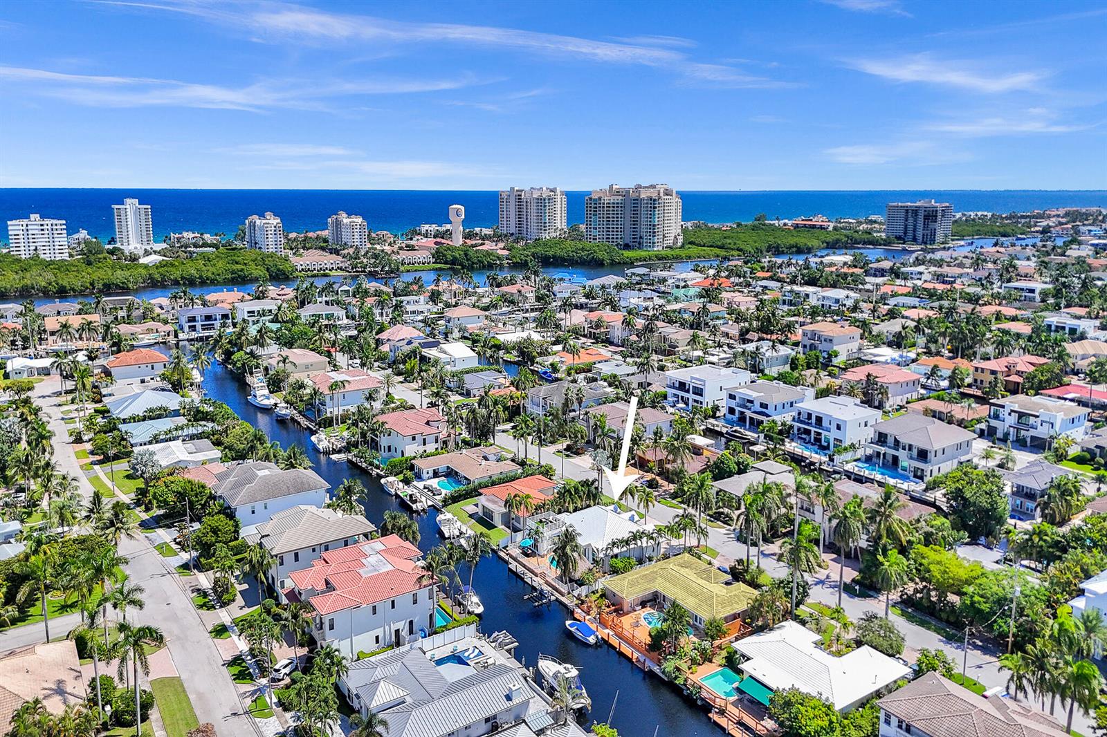 An aerial view shows a waterfront neighborhood with houses, canals, and a distant ocean horizon — 785 NE 71st Street, Boca Raton FL 33487, BOCA RATON, FL