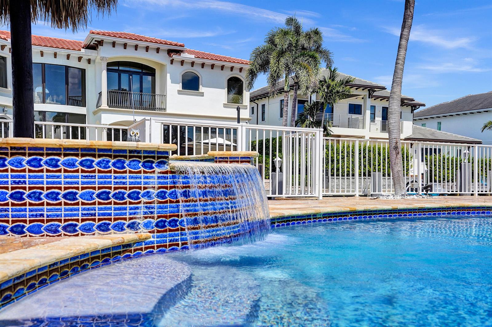 A swimming pool with a tiled water feature sits in front of a large house — 785 NE 71st Street, Boca Raton FL 33487, BOCA RATON, FL