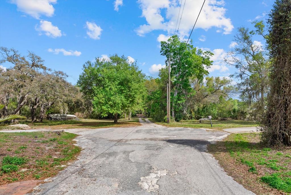 A paved road leads toward a wooded area with a boat parked on the left — INDALE DR, NEW PORT RICHEY, FL