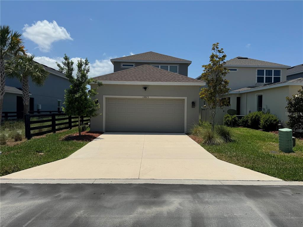 A two-story house with a beige exterior, a two-car garage, and a concrete driveway — 13823 RANGELAND BOULEVARD, ODESSA, FL