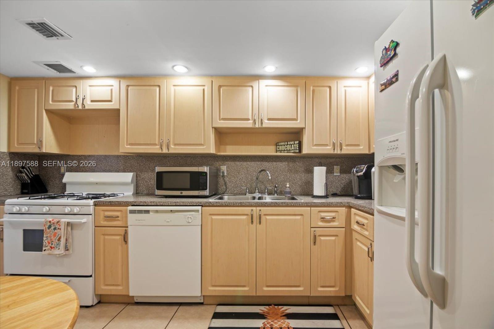 A kitchen features light wood cabinets, a white stove, a dishwasher, and a refrigerator — 3140 S Ocean Dr # 207, Hallandale Beach FL 33009, HALLANDALE BEACH, FL