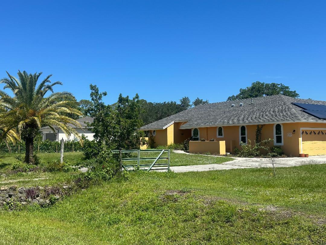 A yellow single-story house with a gray roof and a palm tree in the yard — 15185 Tangelo Boulevard, FL 33412, FL