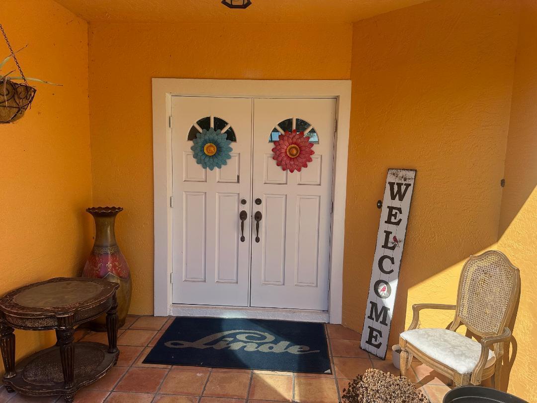 A front porch features double white doors, a welcome sign, a small table, and a chair — 15185 Tangelo Boulevard, FL 33412, FL