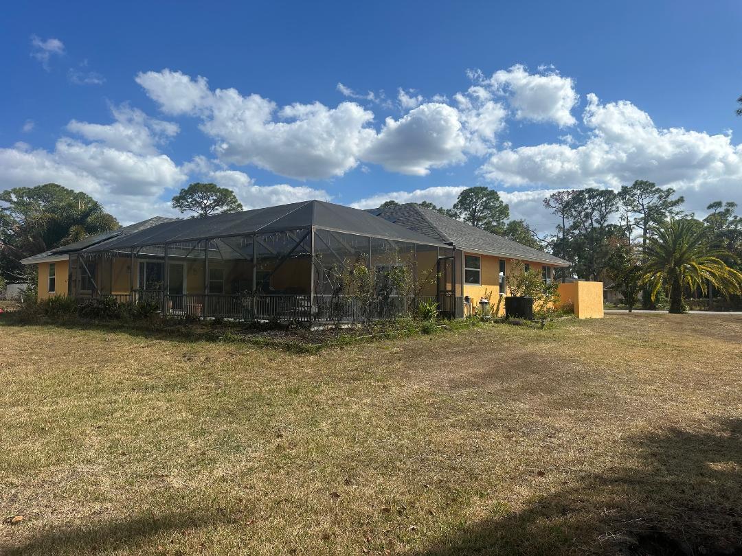 A yellow house with a screened-in lanai sits on a large, dry grassy lot — 15185 Tangelo Boulevard, FL 33412, FL