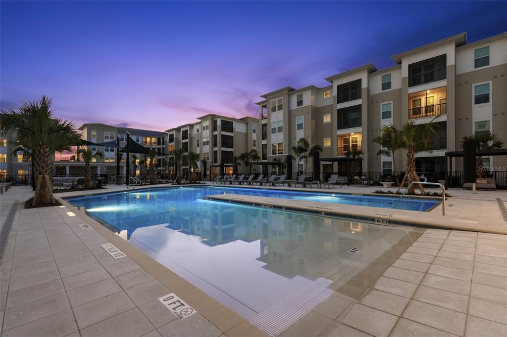 A swimming pool with a shallow entry sits in front of a multi-story apartment building — 7210 INTERBAY BOULEVARD UNIT B1, TAMPA, FL