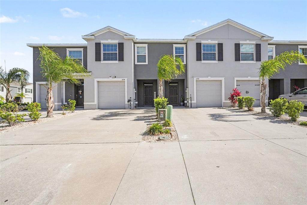A row of two-story townhomes features gray stucco facades, attached garages, and concrete driveways — 16180 GLOWING GROVE AVENUE, ODESSA, FL
