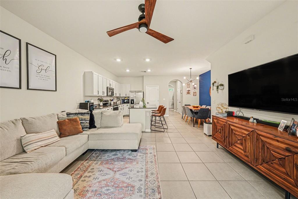 An open-concept living room features a sectional sofa, a wooden media console, and a kitchen — 16180 GLOWING GROVE AVENUE, ODESSA, FL