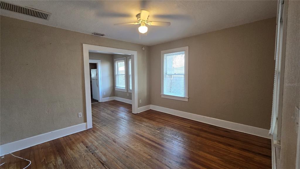 A living room with hardwood floors, tan walls, a ceiling fan, and a doorway leading elsewhere — 3940 BURLINGTON AVENUE N, ST PETERSBURG, FL