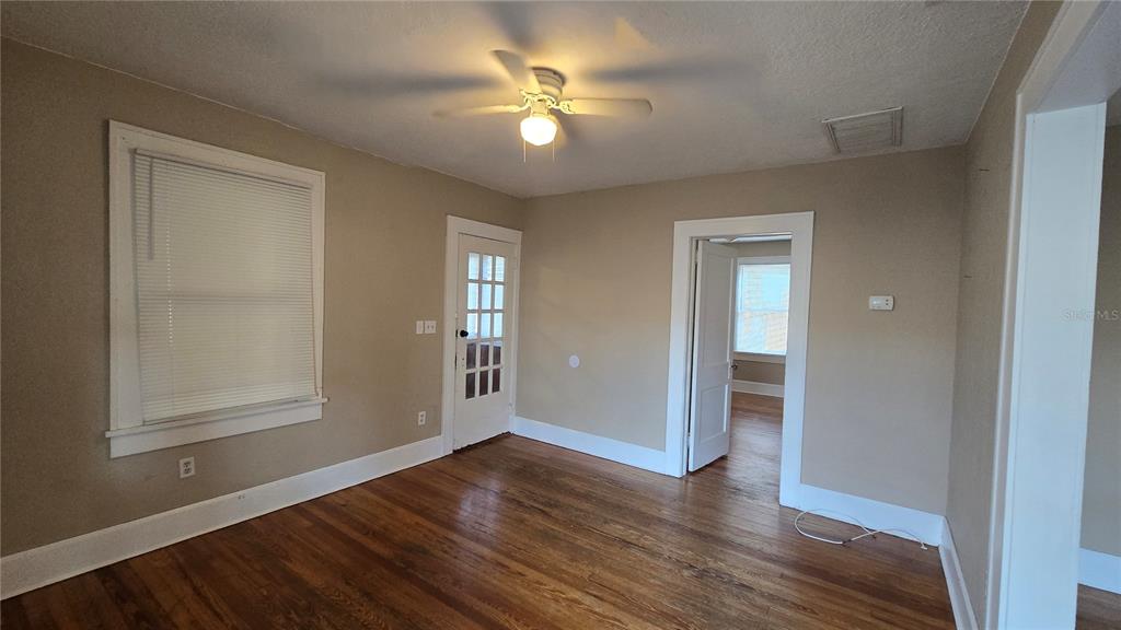 An empty room with hardwood floors, a ceiling fan, and a glass-paneled door — 3940 BURLINGTON AVENUE N, ST PETERSBURG, FL