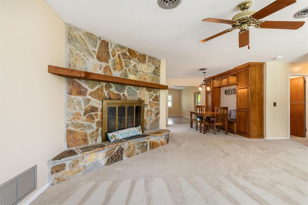 A living room features a stone fireplace, a wooden mantel, and a built-in dining area — 1505 PINE STREET E, NOKOMIS, FL