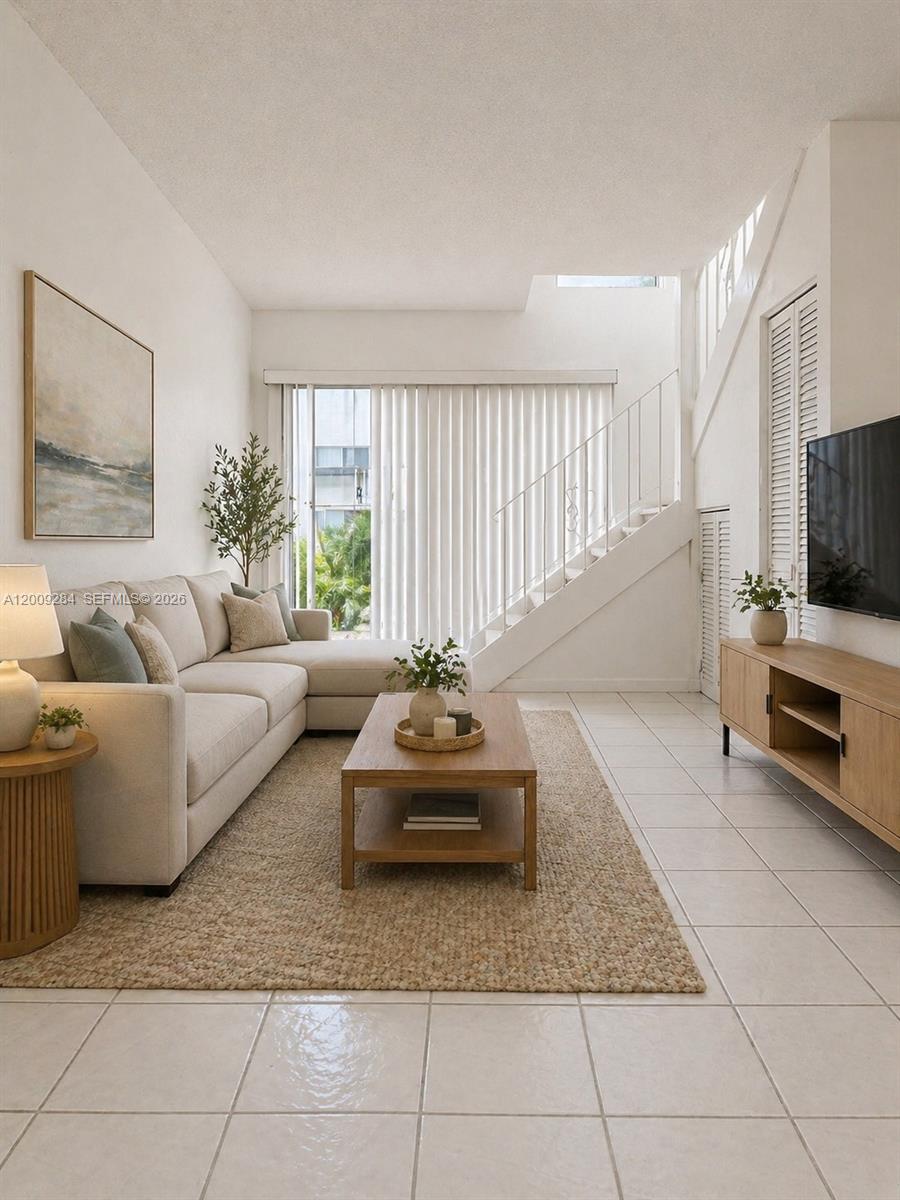 A living room features a sectional sofa, wooden coffee table, television console, and a staircase — 1300 W 47th Pl # 218A, Hialeah FL 33012, HIALEAH, FL