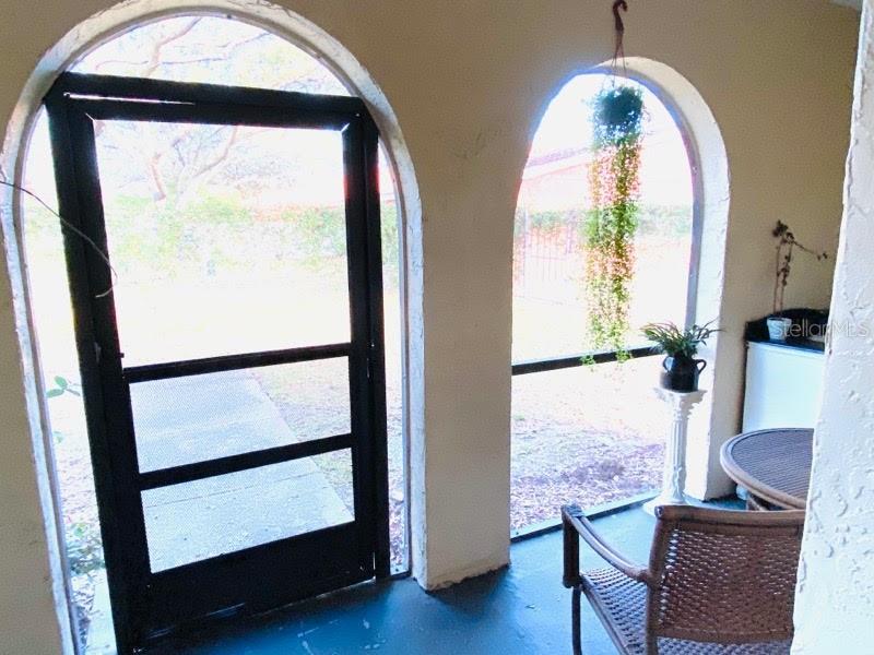 A screened-in porch features arched openings, a dark screen door, and outdoor wicker furniture — 6438 71ST STREET N, PINELLAS PARK, FL
