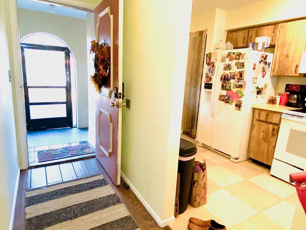 An entryway with a front door opens into a kitchen featuring white appliances and cabinets — 6438 71ST STREET N, PINELLAS PARK, FL