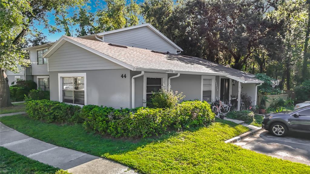 A two-story gray residential building with a front lawn, hedges, and a parked car — 15101 MORNING DR, LUTZ, FL