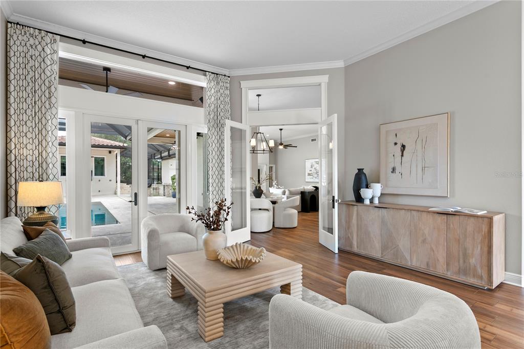 A living room features a light-colored sofa, textured armchairs, a wooden coffee table, and patio doors — 1230 DARLINGTON OAK CIRCLE NE, ST PETERSBURG, FL