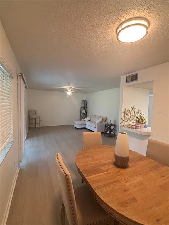 A dining area with a wooden table leads into a living room with light flooring — 628 FAIRWAYS CIRCLE UNIT B, OCALA, FL