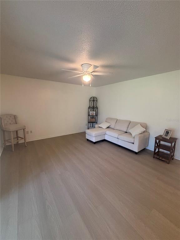 A living room features light wood-look flooring, a white sectional sofa, and a ceiling fan — 628 FAIRWAYS CIRCLE UNIT B, OCALA, FL