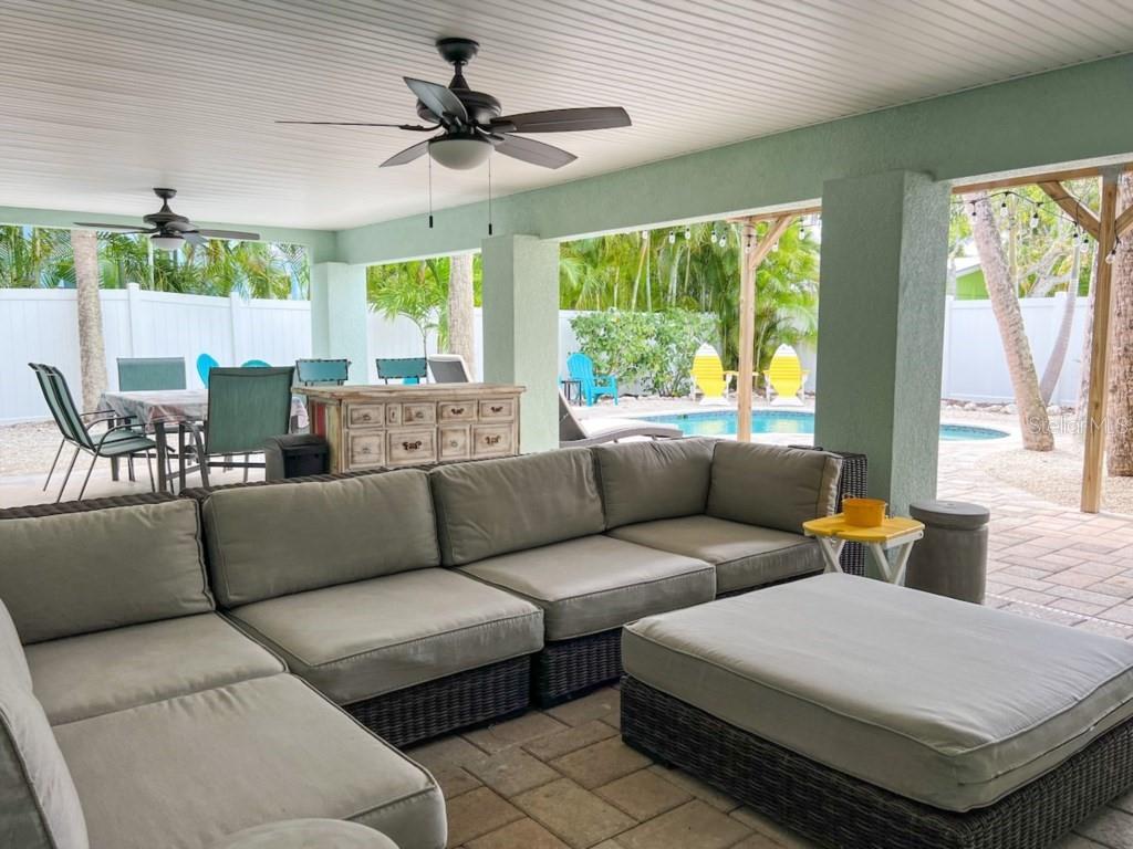 A covered outdoor patio features a large sectional sofa, dining area, and a swimming pool — 308 60TH STREET UNIT A, HOLMES BEACH, FL
