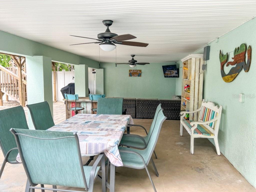 A covered outdoor patio features a dining table, seating, and a bar area — 308 60TH STREET UNIT A, HOLMES BEACH, FL