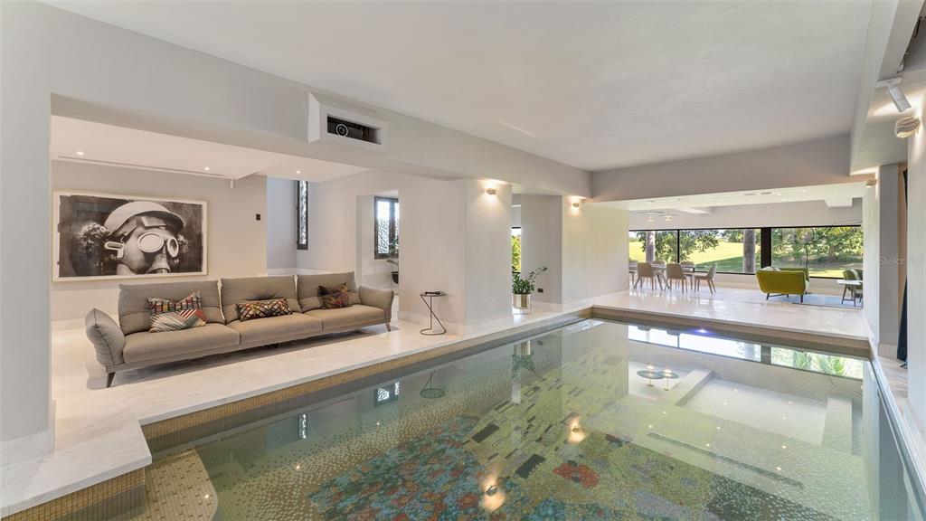 A modern living room features a large indoor swimming pool with mosaic tile flooring — #13 Quintas del Deportivo CARR 102 KM 14.3 SECTOR JOYUDA, BO. MIRADERO, CABO ROJO, PR