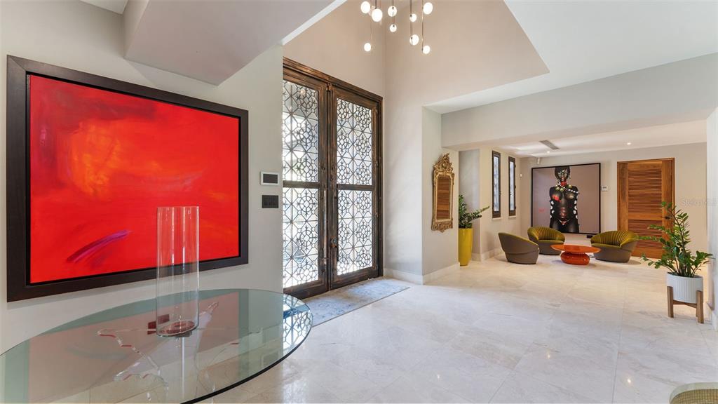 A bright foyer features a large red painting, glass table, and ornate metal double doors — #13 Quintas del Deportivo CARR 102 KM 14.3 SECTOR JOYUDA, BO. MIRADERO, CABO ROJO, PR