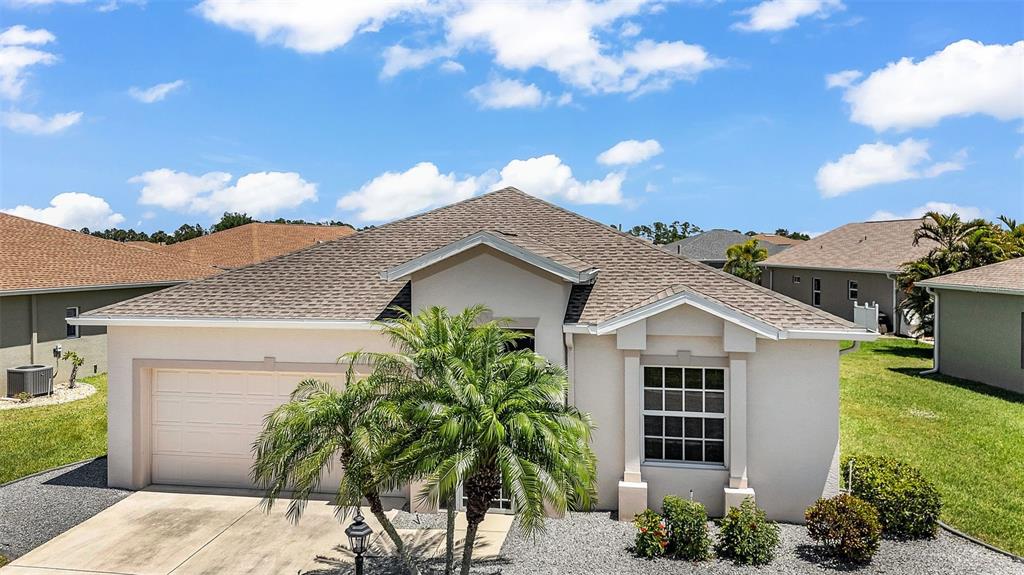 A single-story house with a beige stucco exterior, a two-car garage, and a palm tree — 1713 SUNDERLAND DRIVE, PUNTA GORDA, FL