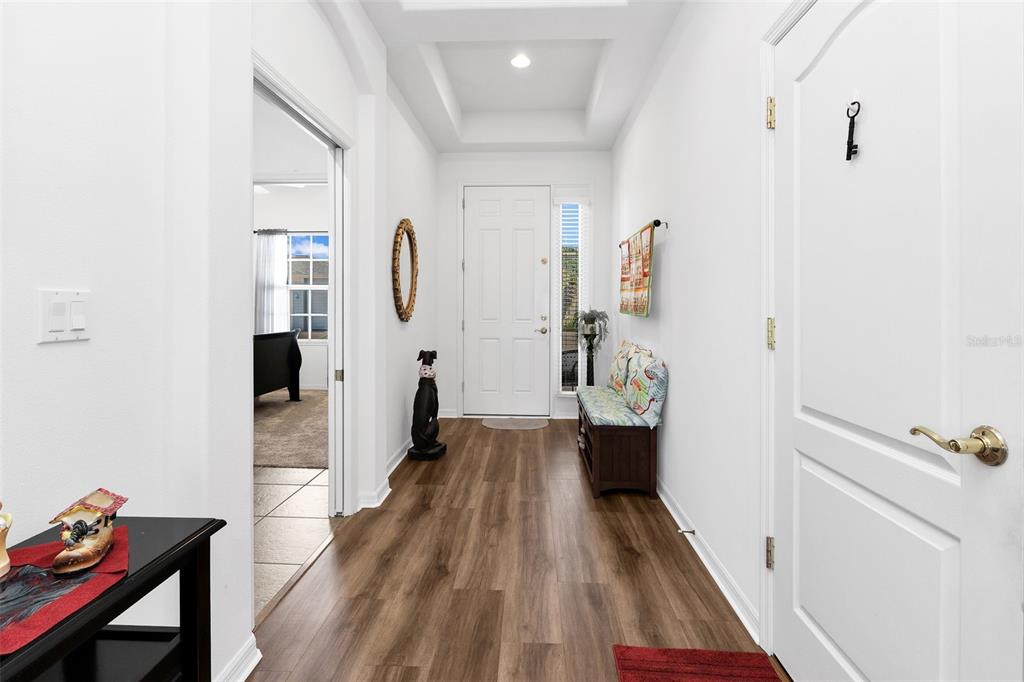 A bright entryway features wood-look flooring, a white front door, and a tray ceiling — 1713 SUNDERLAND DRIVE, PUNTA GORDA, FL