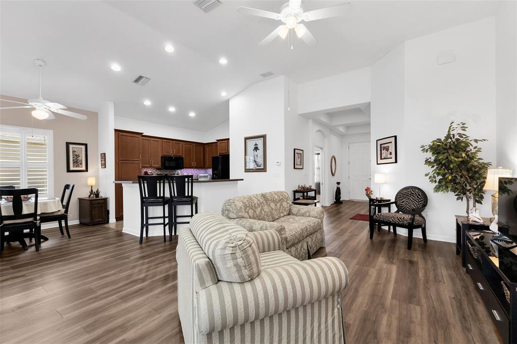 An open-concept living room and kitchen featuring wood-look flooring and a vaulted ceiling — 1713 SUNDERLAND DRIVE, PUNTA GORDA, FL