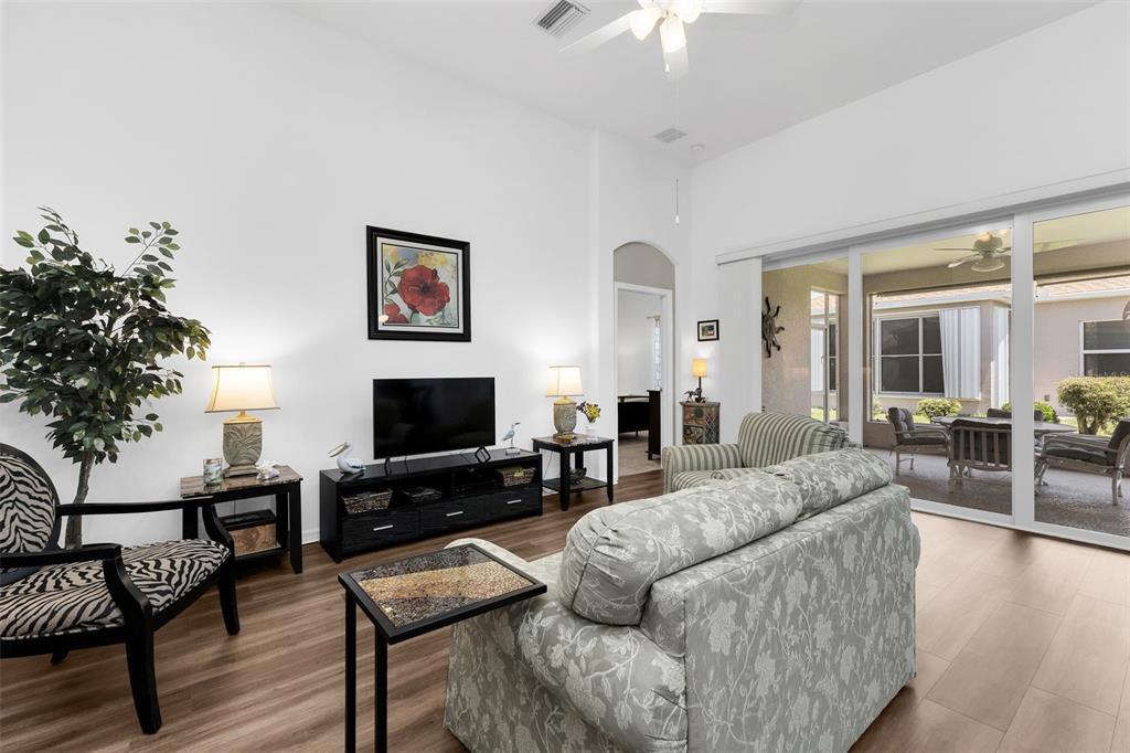 A living room features a floral sofa, zebra-print chair, television console, and sliding glass doors — 1713 SUNDERLAND DRIVE, PUNTA GORDA, FL