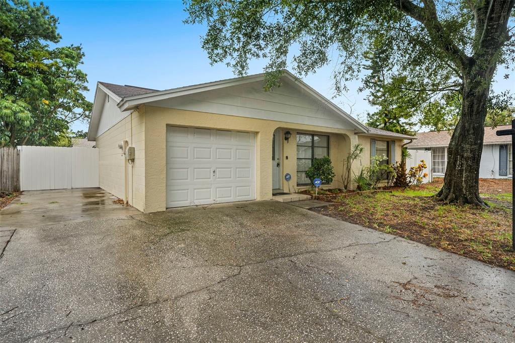 A single-story house with a yellow stucco exterior, a one-car garage, and a concrete driveway — 9403 AFTON COURT, TAMPA, FL