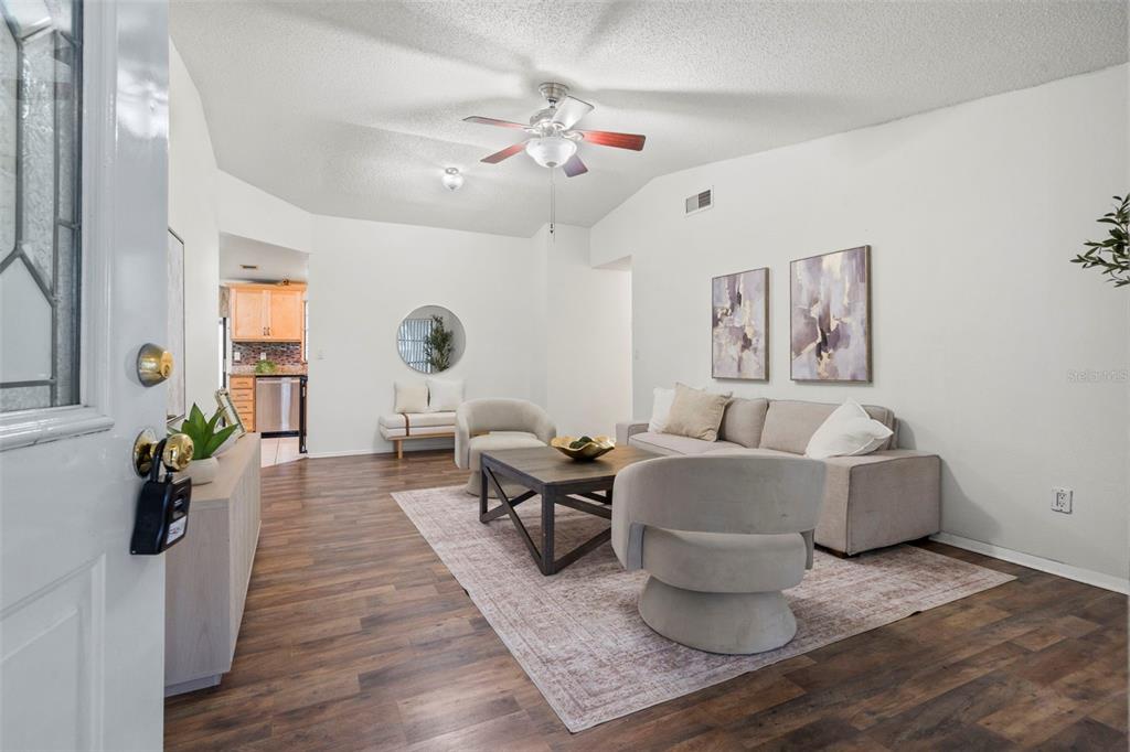 A living room with wood-look flooring, a ceiling fan, and neutral furniture on a rug — 9403 AFTON COURT, TAMPA, FL