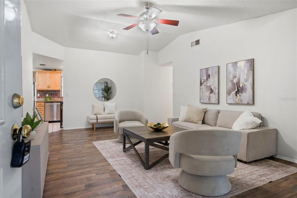A living room features wood-look flooring, a ceiling fan, a sofa, and two armchairs — 9403 AFTON COURT, TAMPA, FL