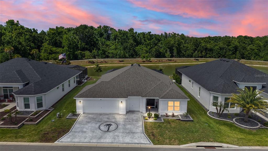 An aerial view of a single-story house with a palm tree driveway design at sunset — 6857 BAYSINGER PATH, THE VILLAGES, FL