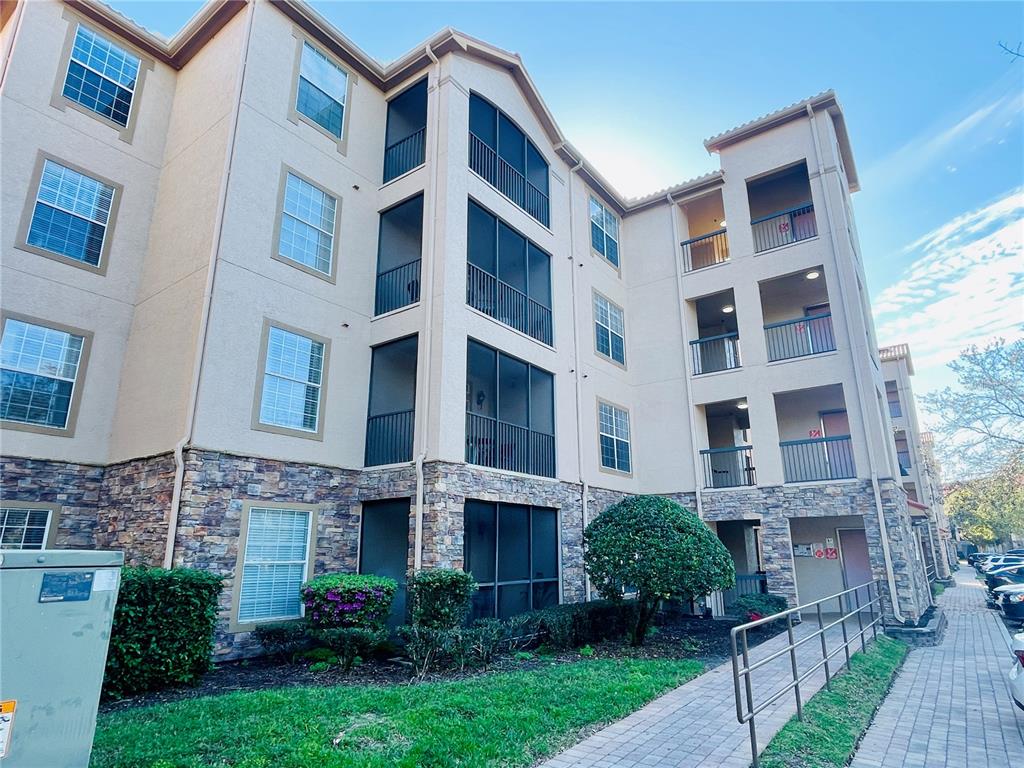A multi-story apartment building features beige stucco walls, stone veneer siding, and screened-in balconies — 8010 TUSCANY WAY UNIT 5301, DAVENPORT, FL