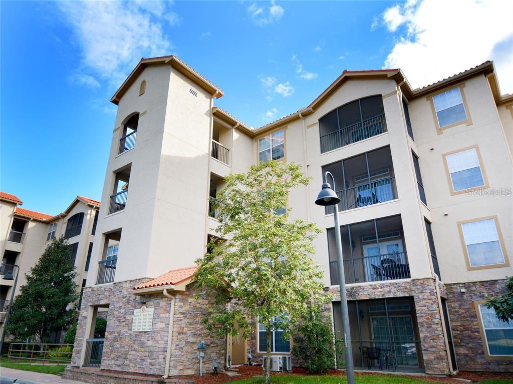 A multi-story apartment building with stucco walls, stone veneer accents, and screened-in balconies — 8010 TUSCANY WAY UNIT 5301, DAVENPORT, FL