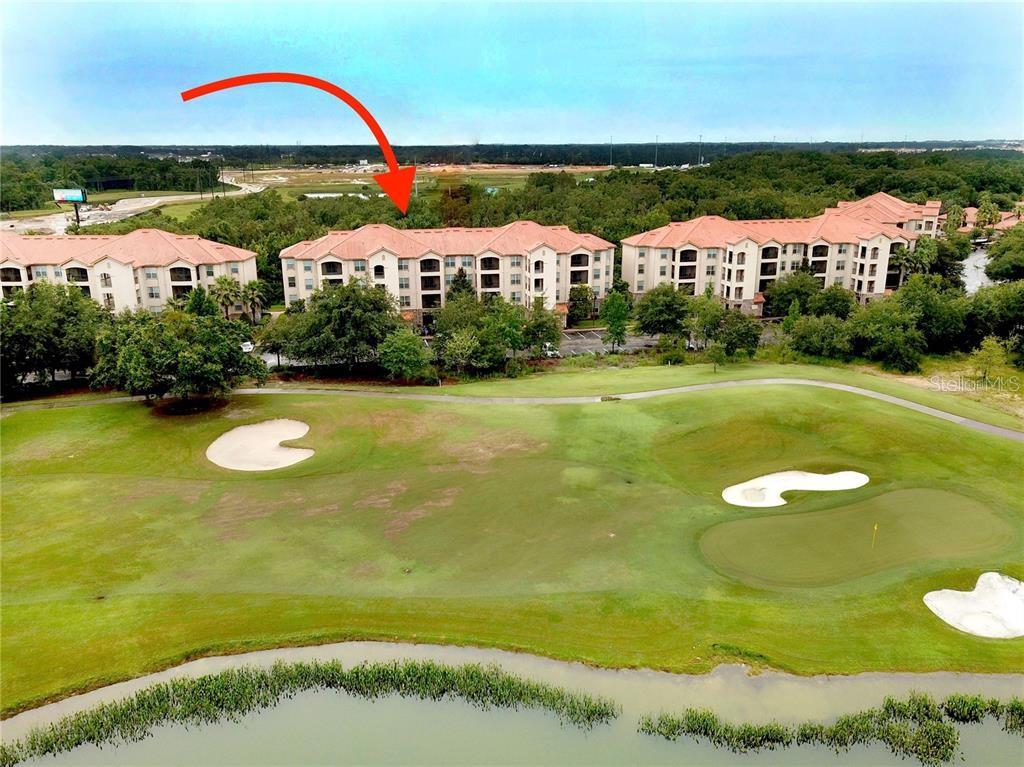 An aerial view shows a multi-story apartment building overlooking a golf course and pond — 8010 TUSCANY WAY UNIT 5301, DAVENPORT, FL