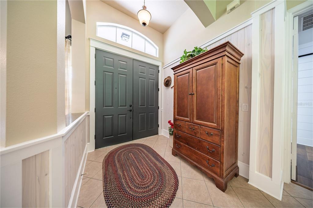 A foyer features a dark double door, a large wooden armoire, and tile flooring — 1619 STARGAZER TERRACE, SANFORD, FL