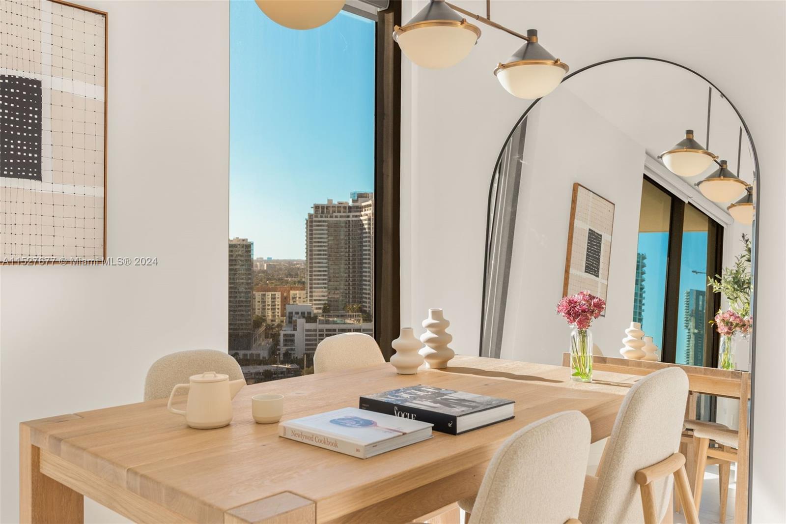 A dining room features a wooden table, arched floor mirror, and city view through windows — 501 NE 31st St # 2209, Miami FL 33137, MIAMI, FL