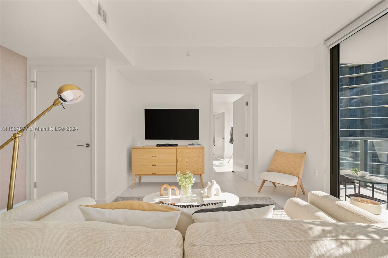 A bright living room features a light wood console, a white sofa, and a balcony — 501 NE 31st St # 2209, Miami FL 33137, MIAMI, FL