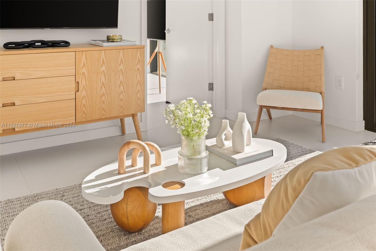 A modern living room features a white organic-shaped coffee table, light wood furniture, and chairs — 501 NE 31st St # 2209, Miami FL 33137, MIAMI, FL