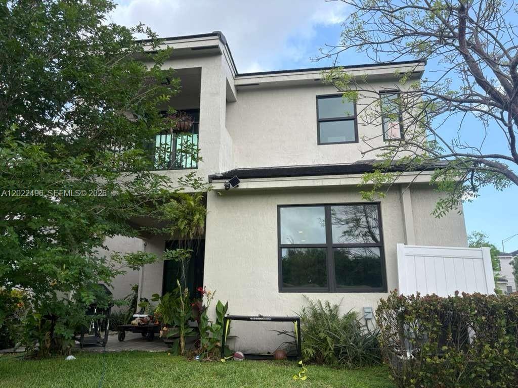The exterior of a two-story house features a balcony, a patio, and a grassy yard — 115 NW 36th Ave # 115, Pompano Beach FL 33069, POMPANO BEACH, FL