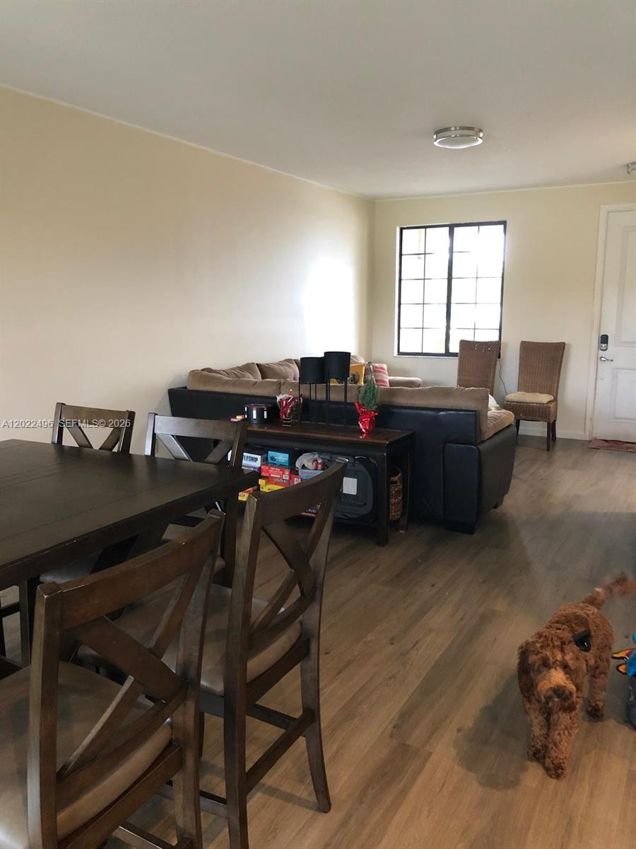 A living and dining area features wood-look flooring, a dark table, and a sectional sofa — 115 NW 36th Ave # 115, Pompano Beach FL 33069, POMPANO BEACH, FL